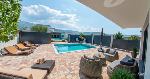 a backyard with a swimming pool and chairs and a patio at Villa Vie Luxury Retreat in Blagaj