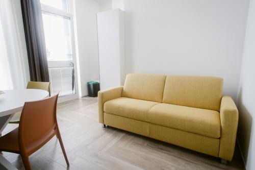a living room with a yellow couch and a table at Erigia House - Appartamenti Eleganti - Molfetta in Molfetta