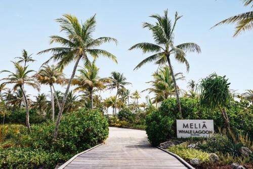 a walkway through a resort with palm trees at Meliá Whale Lagoon Maldivas in Fenfushi