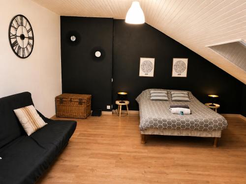 a bedroom with a bed and a couch and a clock at Le Petit Loft Vosgien -Escapade nature & cosy in Cornimont