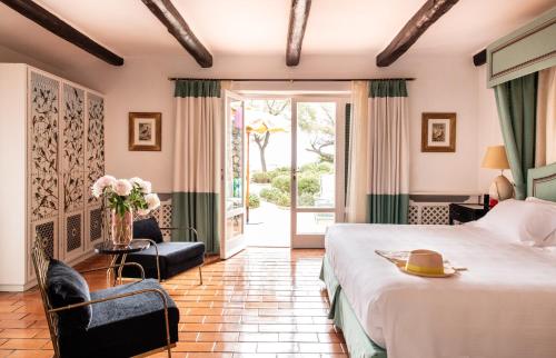 a hotel room with a large bed and a sliding glass door at Il Pellicano in Porto Ercole