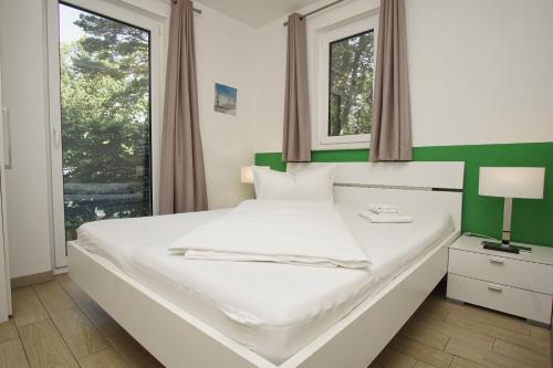 a bedroom with a large white bed with a green headboard at Ferienhaus am Dünenstrand in Baabe