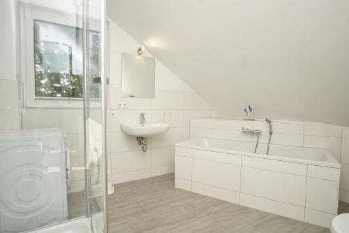 a white bathroom with a sink and a bath tub at Ferienhaus am Dünenstrand in Baabe
