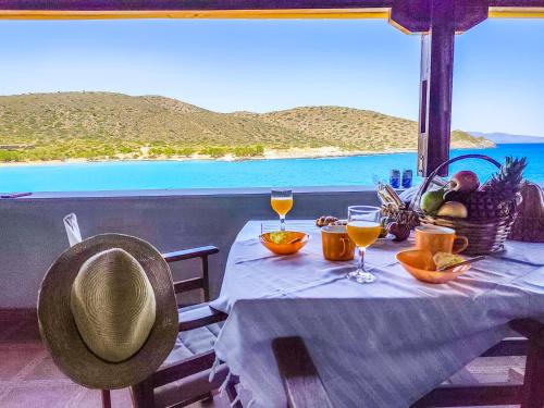 a table with a basket of fruit and wine glasses at Tholos Alexandra's Beachfront House in Kavoúsion