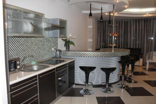 a kitchen with a sink and a counter with stools at Cozy Apartment in Most City Center in Dnipro