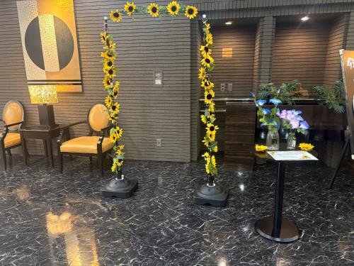 a room with sunflowers and a table and chairs at APA Hotel Nagoya Sakae Ekimae EXCELLENT in Nagoya