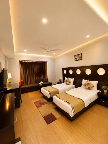 a bedroom with two beds and a television in it at Hotel Cymbal -Sector 31 Gurgaon in Gurgaon