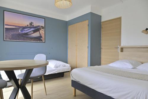 a bedroom with two beds and a table and a table at MOTEL ASCOT - Hotel & Appartements in Cagnes-sur-Mer