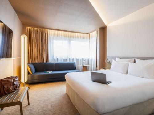 a hotel room with a large bed and a couch at Novotel Gent Centrum in Ghent