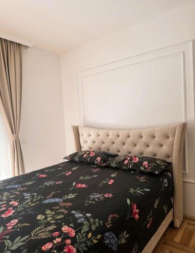a bedroom with a bed with a black floral bedspread at Stan na dan Podgorica Mne in Podgorica