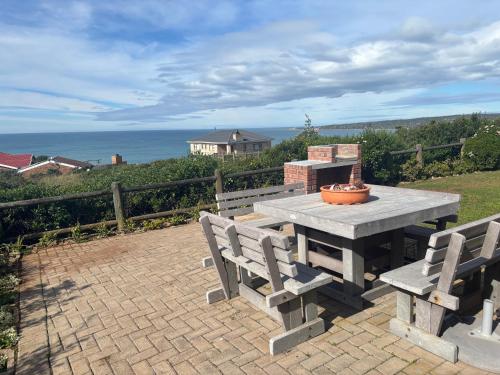 a picnic table with two benches and the ocean at Sea Gem with a stunning view in Boggomsbaai