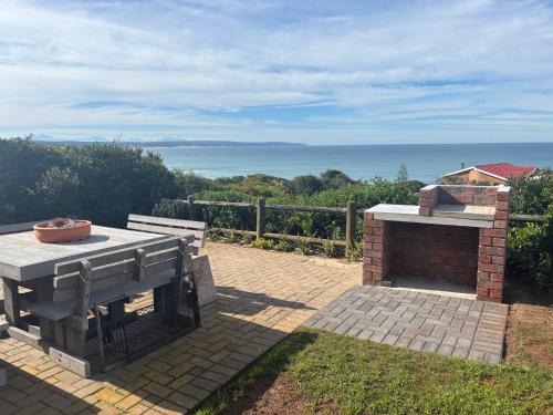 a patio with a grill and a table and bench at Sea Gem with a stunning view in Boggomsbaai