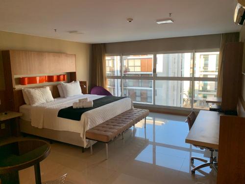 a bedroom with a large bed and a large window at Flat Sofisticado no Jade Hotel Home Office in Brasília