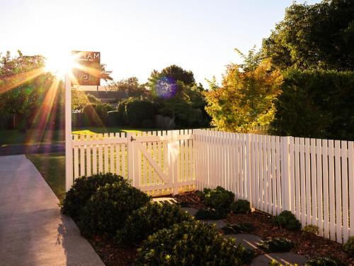 a white fence in a yard with the sun behind it at Maple & Rubus, Berry - by Linnaeus Collection in Berry