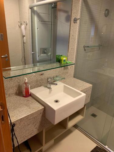 a bathroom with a sink and a shower and a mirror at Flat Sofisticado no Jade Hotel Home Office in Brasília