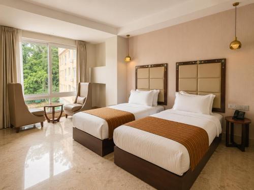a hotel room with two beds and a window at Lotus Villa in Phuntsholing