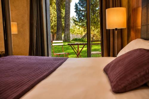 a bedroom with a bed and a view of a garden at Hotel & Spa La Salve in Torrijos