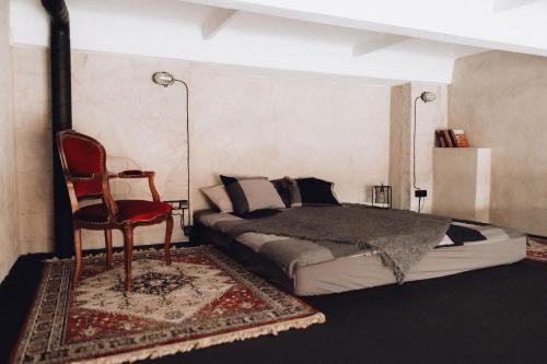 a bedroom with a bed and a red chair at Maruse's Apartment in Kuldīga