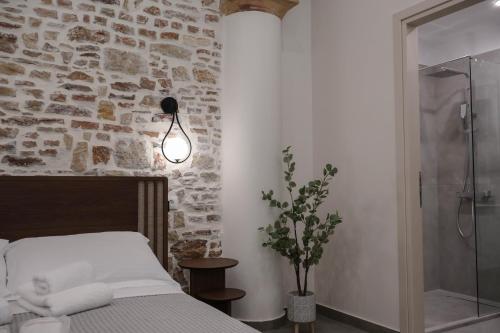 a bedroom with a bed and a stone wall at Ralli 34 ROOMS&APTS in Chios