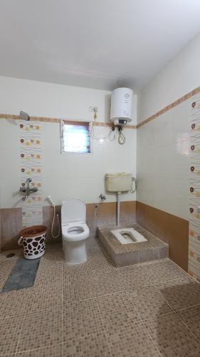 a bathroom with a toilet and a sink in it at BMK Inn in Bangalore