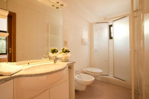 La salle de bains blanche est pourvue de toilettes et d'un lavabo. dans l'établissement Hotel Residence Rely, à Brenzone