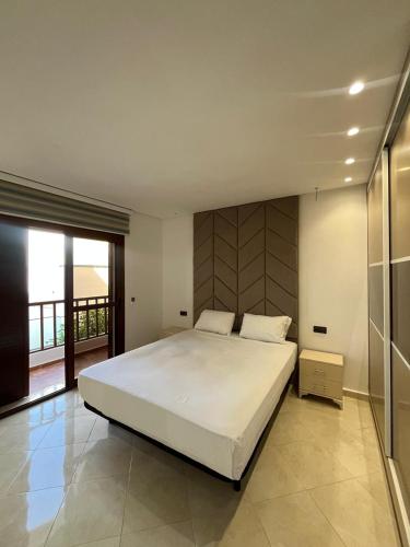 a bedroom with a large white bed and a balcony at Studio marina smir in Marina Smir