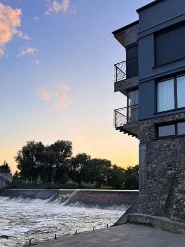 a building next to a river with a waterfall at Viešbutis Banga in Tauragė