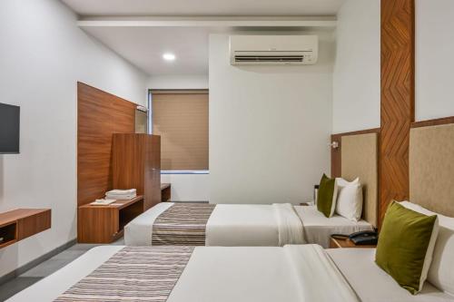 a hotel room with two beds and a television at Hotel Fountain - Kamrej in Surat