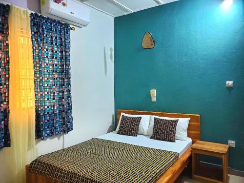 a bedroom with a bed with a blue wall at Maison fleurie Ouidah in Ouidah