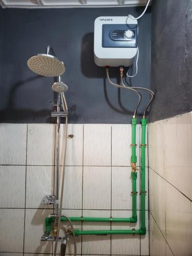 a shower in a bathroom with a green hose at Maison fleurie Ouidah in Ouidah