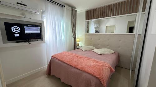 a bedroom with a bed with a tv on the wall at Apto Margaridas|3Q,todo Climatizado,ao lado Termas in Piratuba