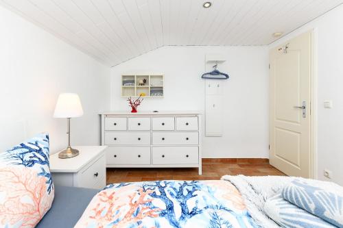 a white bedroom with a bed and a dresser at Ferienhaus Sternenklar in Wittmund