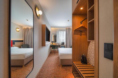 a hotel room with a mirror and a bedroom at Qubus Hotel Gliwice in Gliwice