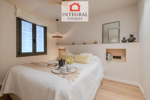 a bedroom with a white bed with a table on it at Apartament Eden Mar in Platja d'Aro