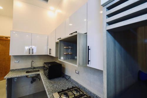a kitchen with white cabinets and a sink at Nile Kingdom Guest house in Luxor