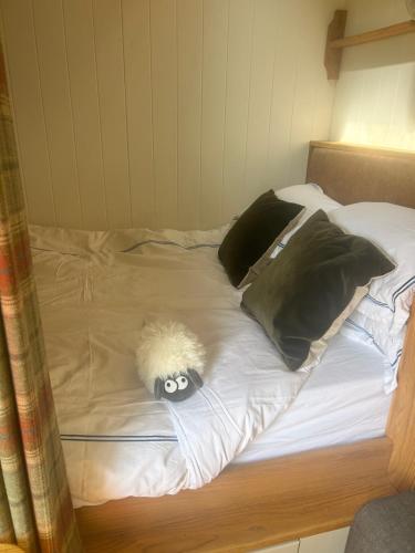 a bed with pillows and a stuffed animal on it at Astwell Mill Luxury Shepherds Hut in Helmdon
