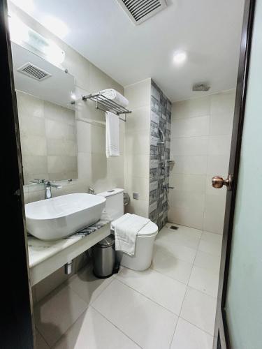 a white bathroom with a sink and a toilet at Royal Mark Hotel in Sylhet