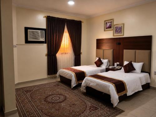 a hotel room with two beds and a window at شركة العييري للشقق المخدومة شركة شخص واحد الاحساء 2 in Al Ahsa
