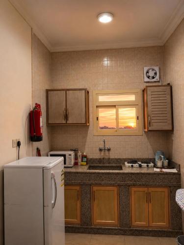 a kitchen with a white refrigerator and a window at شركة العييري للشقق المخدومة شركة شخص واحد الاحساء 2 in Al Ahsa