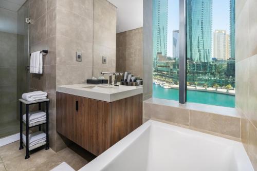 a bathroom with a tub and a sink and a window at Charthouse Bahrain in Manama