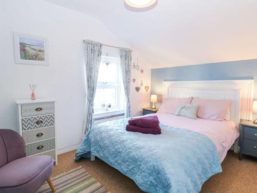a bedroom with a bed and a chair and a window at Hideaway Cottage in Hunstanton