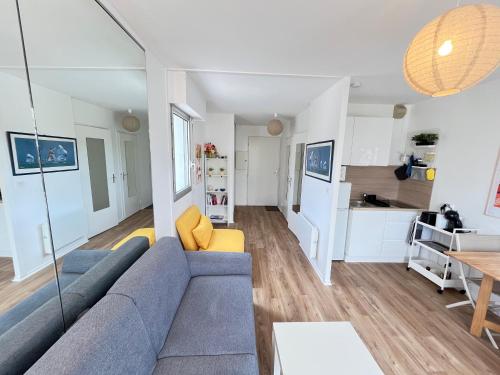 a living room with a blue couch and a kitchen at Le Cocon Baulois in La Baule