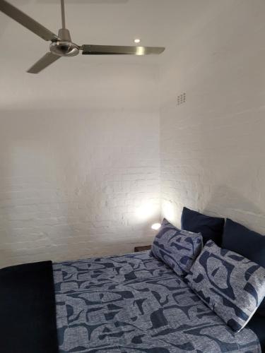 a bedroom with a bed and a ceiling fan at Cowes Cottage in Fish Hoek