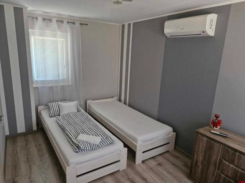 a small room with a bed and a air conditioner at Hársfa Jakuzzis Nyaraló Szarvas in Szarvas