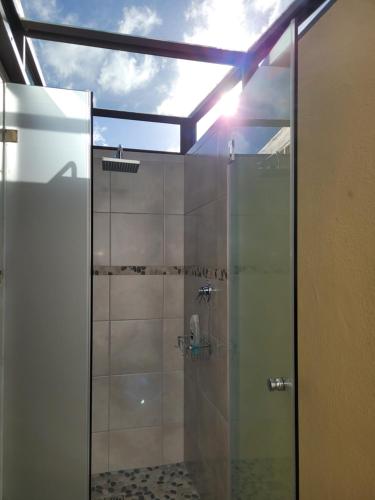 a shower with a glass door in a bathroom at Cowes Cottage in Fish Hoek