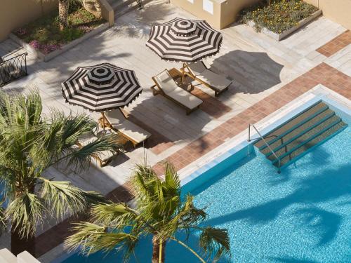 an overhead view of a swimming pool with two umbrellas and chairs at Grecotel Casa Adele in Platanes