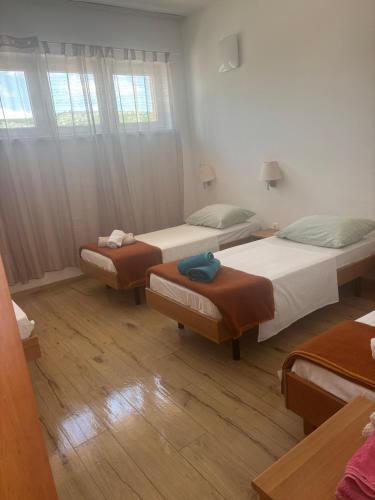 three beds in a room with wooden floors at Tramontana apartments in Dugobabe