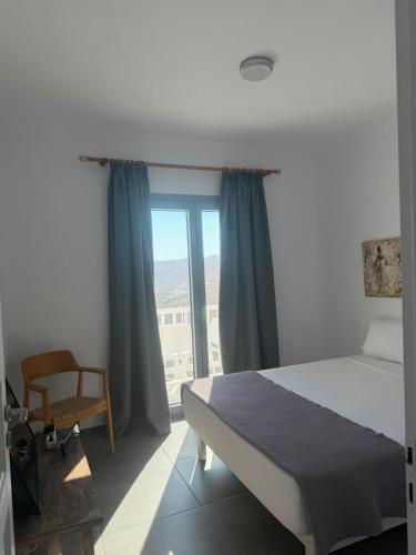 a bedroom with a bed and a window and a chair at Villa Viktoria in Elia beach, Mykonos in Mikonos