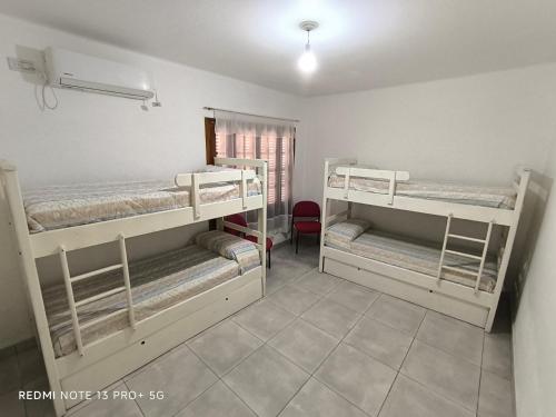 a room with three bunk beds and a red chair at Casa hasta 10 personas. in Villa Rumipal