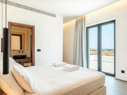 a white bedroom with a bed and a large window at Villa Sabbia in Mesochórion